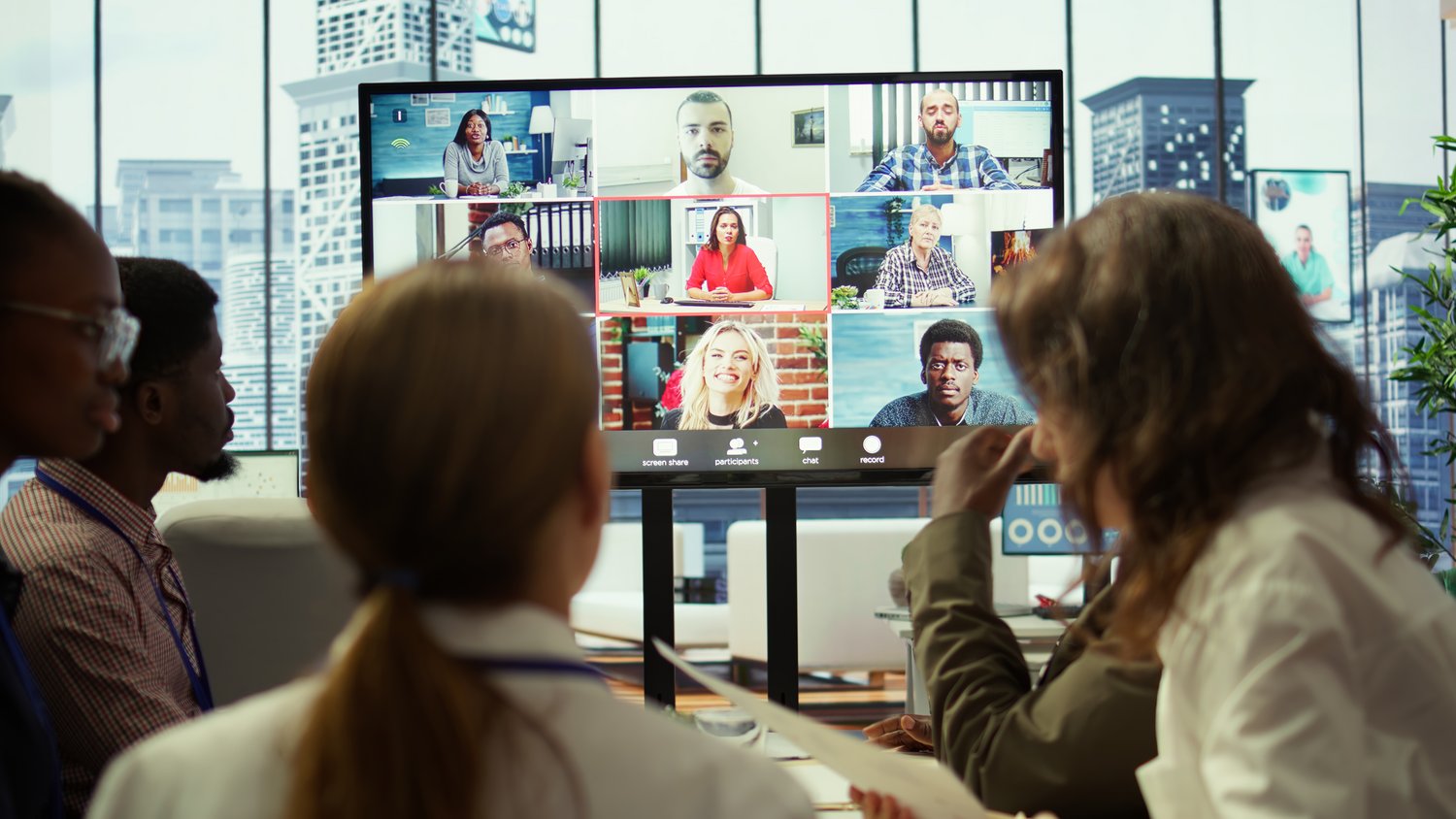 Bild zeigt Teammitglieder die in einem hybriden Setting eine Besprechung haben